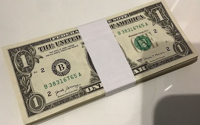 A bundle of one-dollar bills held by a paper strap