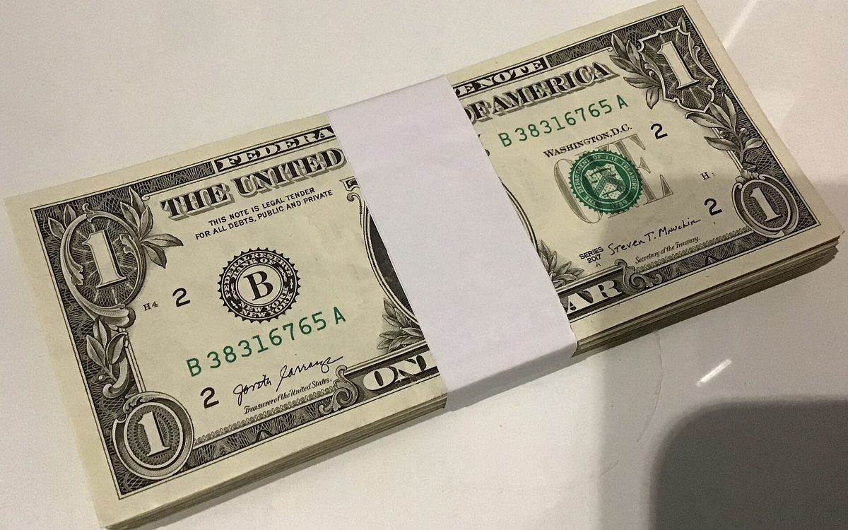 A bundle of one-dollar bills held by a paper strap